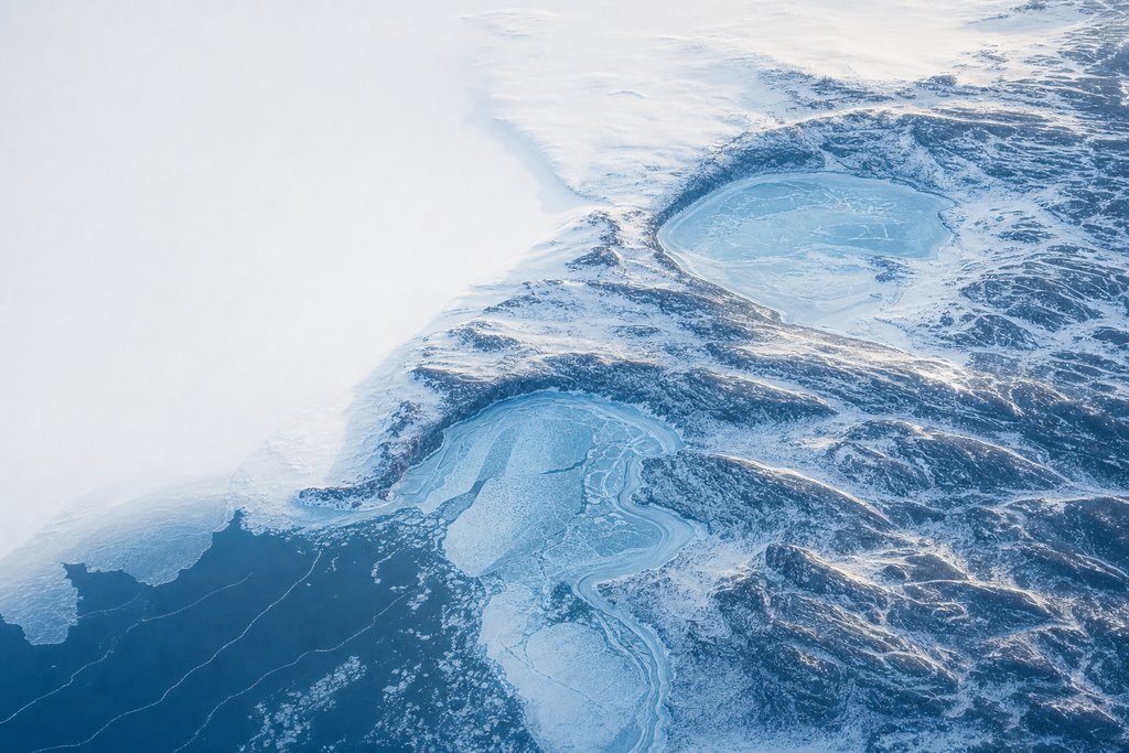 Aerial view of two separate frozen coastal inlets cut into a snow-covered shoreline, divided by an unbroken headland — the plate for where the complaint chain stops in this province