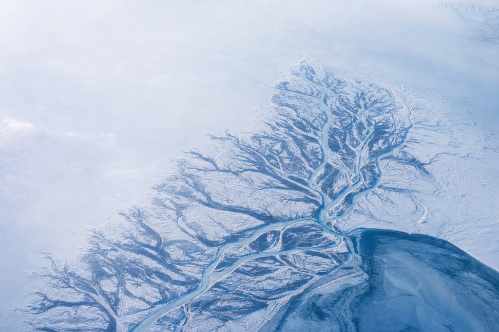 Aerial view of a frozen river delta splitting into many separate bounded channels across a snowfield — the plate for the licences section