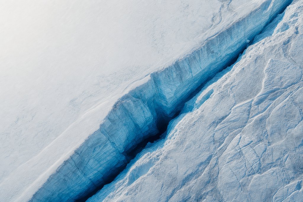 Aerial view of a deep crevasse in a glacier seen from directly above, its blue interior walls revealing dense internal structure far below — the plate for how games are tested in the game fairness section