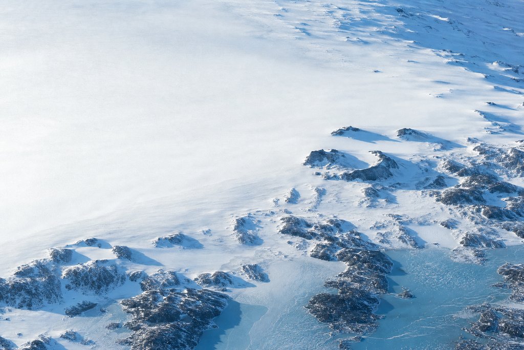 Aerial view of an extremely long shallow snow slope falling at an almost imperceptible constant gradient, the descent readable only across the full width of the frame — the plate for rtp and house edge in the game fairness section