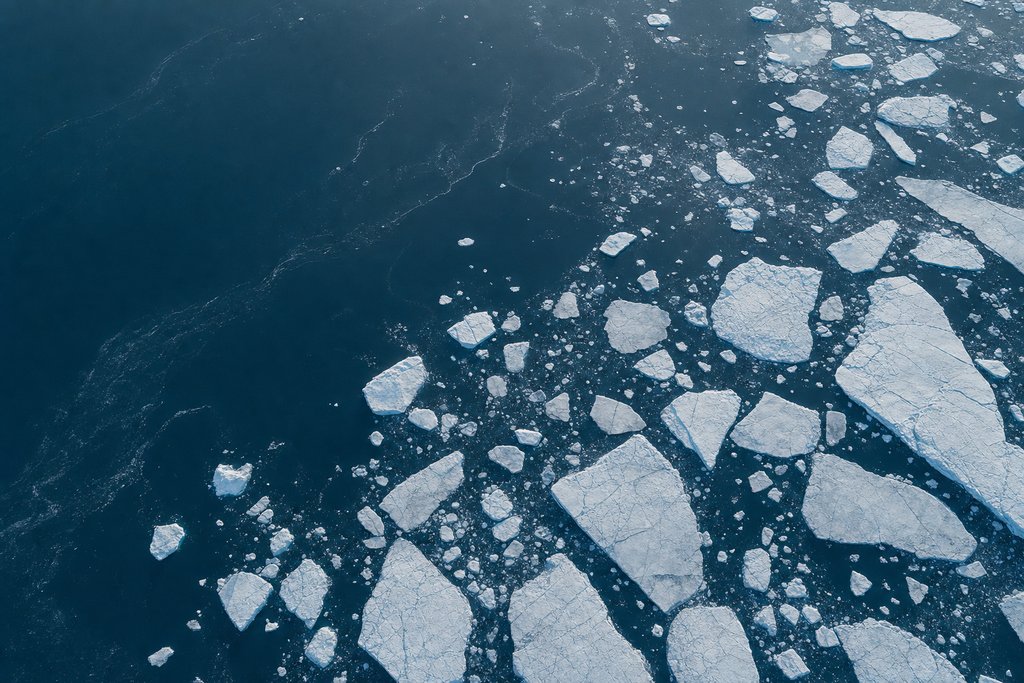 Aerial view of a field of loose broken ice fragments drifting on dark open water, with no fixed edge or shoreline anywhere in the frame — the plate for crypto casinos in the licences section