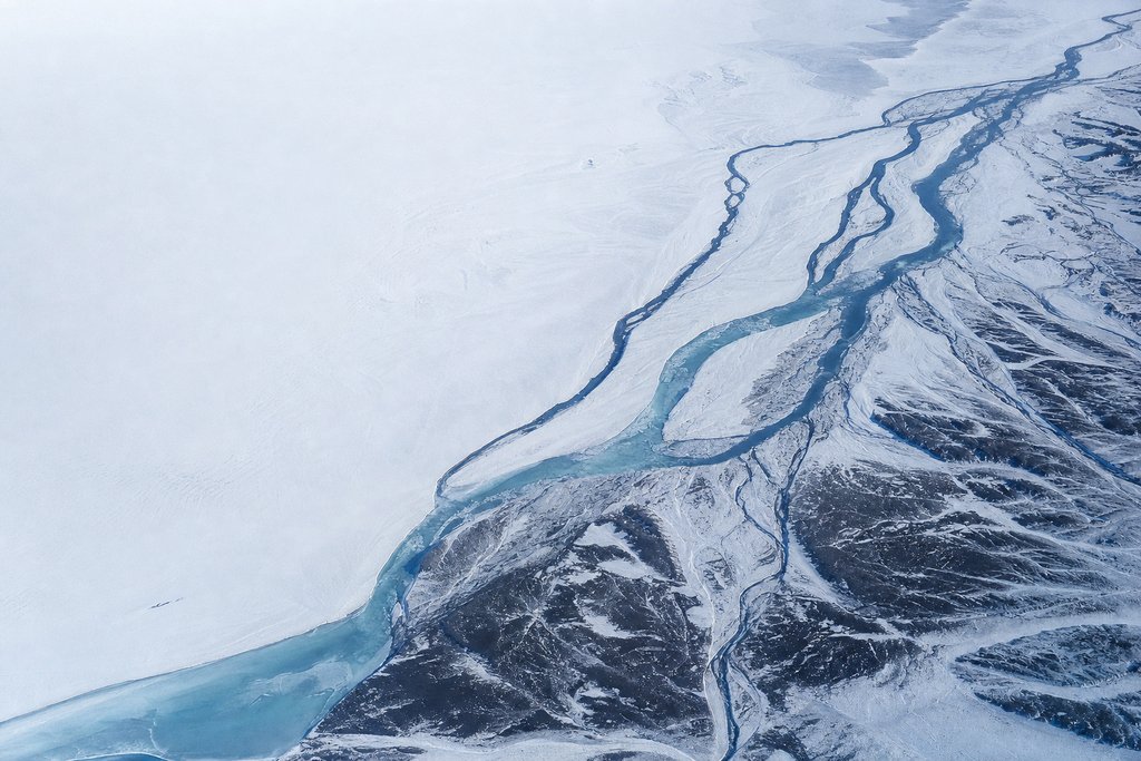 Aerial view of a frozen delta where one channel splits into four separate routes across a snow flat, each a different width — the plate for withdrawal methods in the payouts section