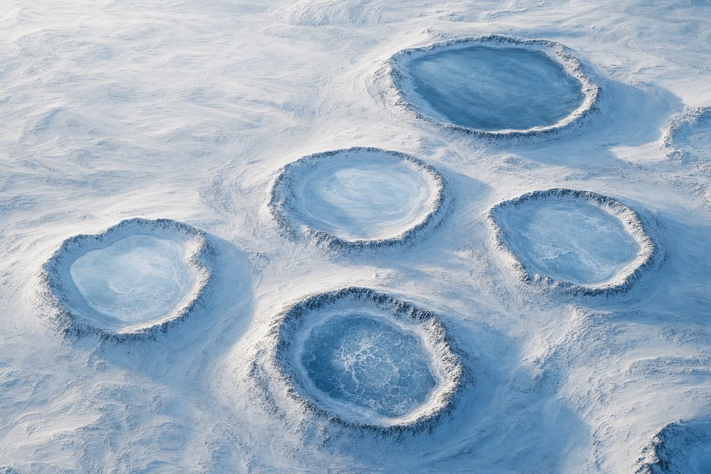 Aerial view of five frozen lakes arranged across a snow plain, each ringed by its own distinct raised shore — the plate for the provincial lottery section
