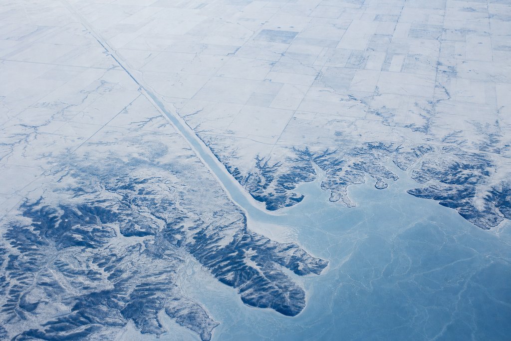 Aerial view of a snow-covered prairie reservoir with one long straight frozen arm reaching far into flat farmland — the plate for PlayAlberta.ca, the provincial site scored on the same rubric