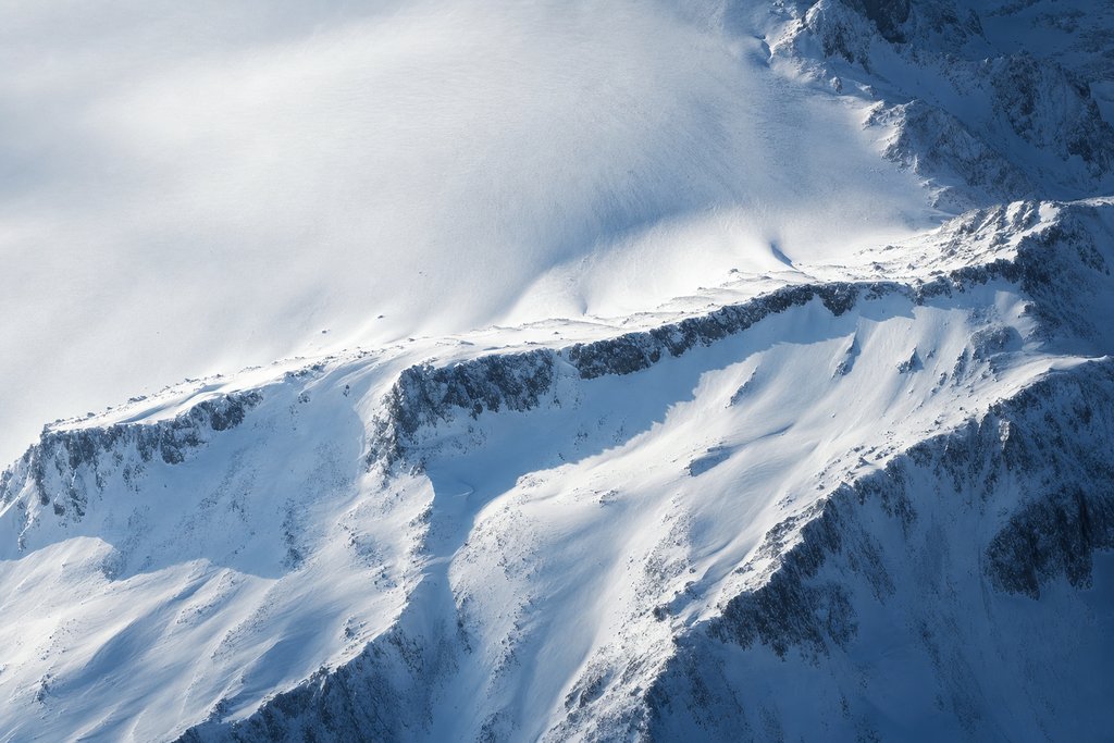 Aerial view of a broad snow slope where one low natural barrier ridge runs across the fall line, visibly holding the snow above it — the plate for responsible gambling page