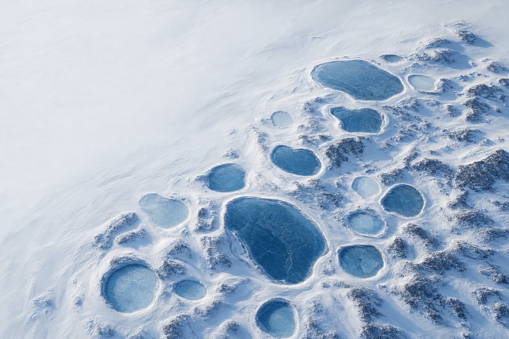 Aerial view of eleven separate frozen pools of clearly different size set into one continuous snowfield — the plate for the operator reviews