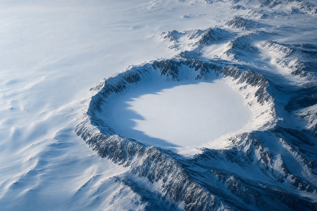 Aerial view of a snow-covered basin ringed completely by a continuous raised ridge, the interior sheltered and smooth — the plate for the safer gambling section