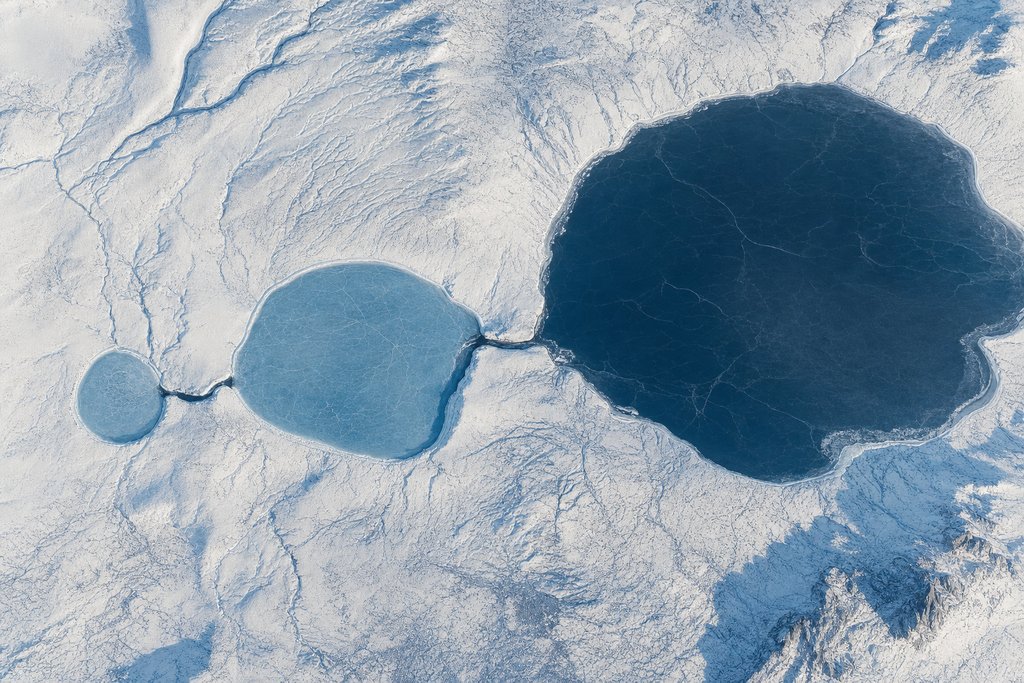 Aerial view of three frozen lakes lying in a chain across a snowfield, each larger than the last, joined by two narrow channels of dark ice — the plate for the Ontario escalation chain