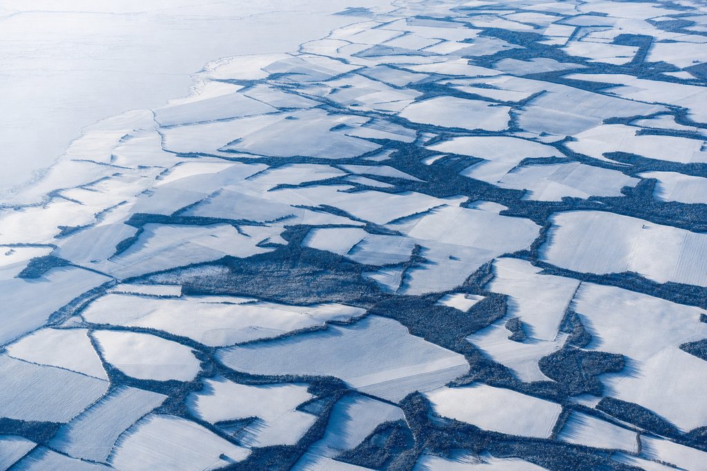 Aerial view of a mosaic of many differently shaped snow-covered land parcels of clearly varying size and tone, separated by dark treelines — the plate for the thirteen jurisdictions