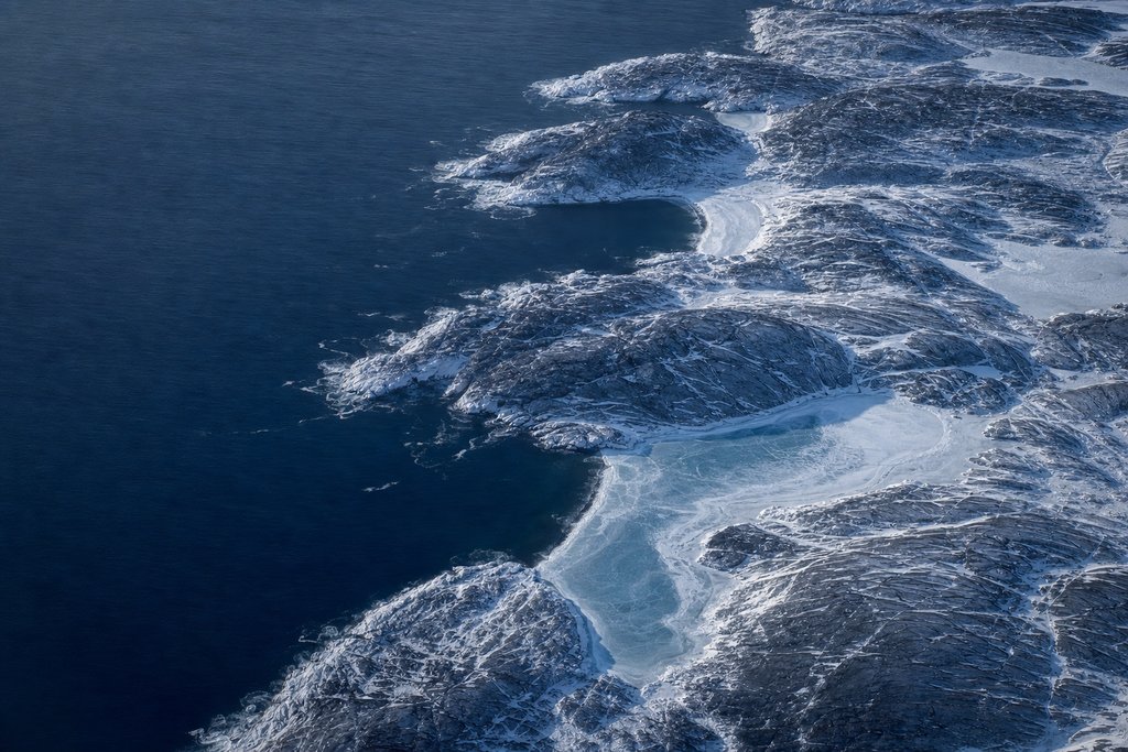 Aerial view of a rugged rocky Atlantic coastline in winter, pale surf breaking along dark granite headlands — the plate for the Nova Scotia safety index
